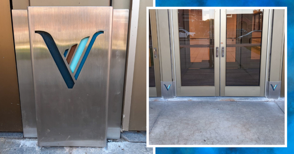 Close-up of the restored door frame after repair, featuring a brushed stainless steel plate with a custom cutout of the OLV logo. The new plate fits seamlessly over the existing frame, showcasing a clean, modern finish with the freshly painted door frame matching the logo's colors.