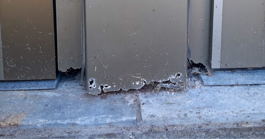 Close-up of a weathered steel door frame before repair, showing rust, corrosion, and deterioration caused by exposure to salt, ice, and snow due to the Buffalo Winter. The damage is visible along the edges and surface, highlighting the need for restoration.