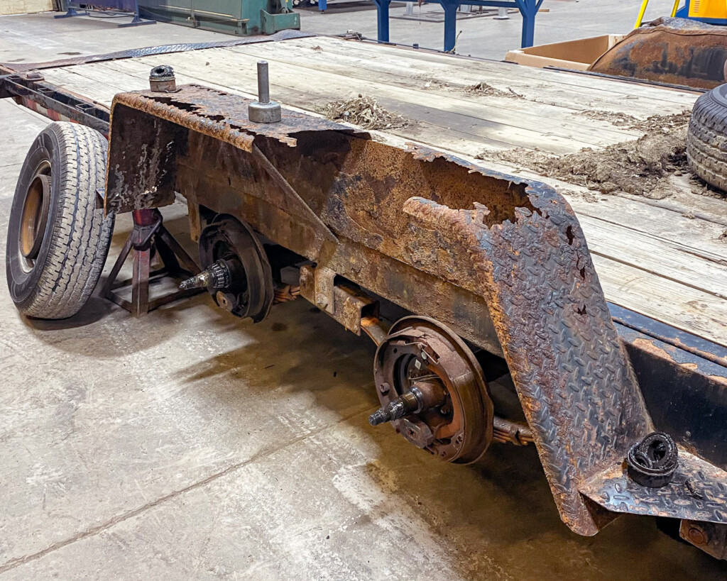 A heavily rusted trailer fender with visible corrosion and damage, showing the effects of harsh road conditions and weather exposure.