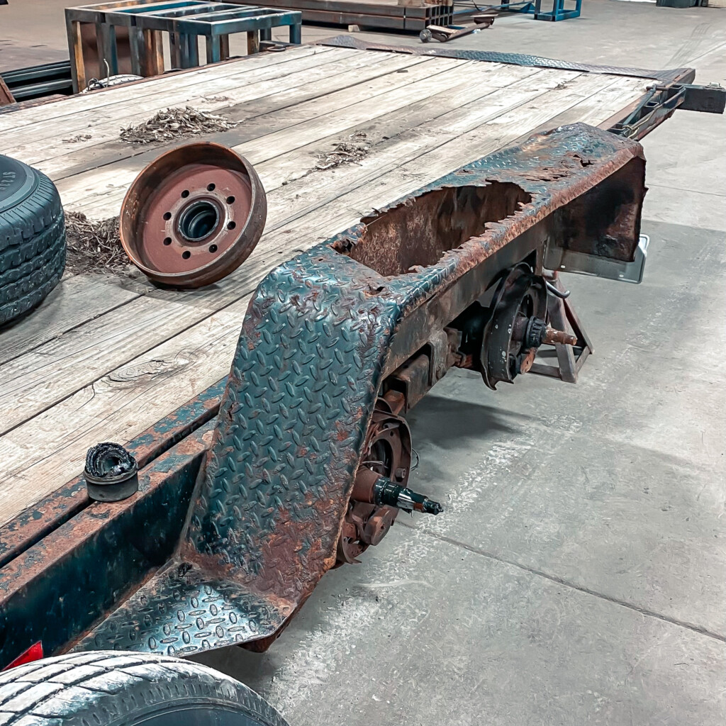 Close-up of a rusted and deteriorating trailer fender, with rust holes and flaking metal highlighting the need for repair or replacement.