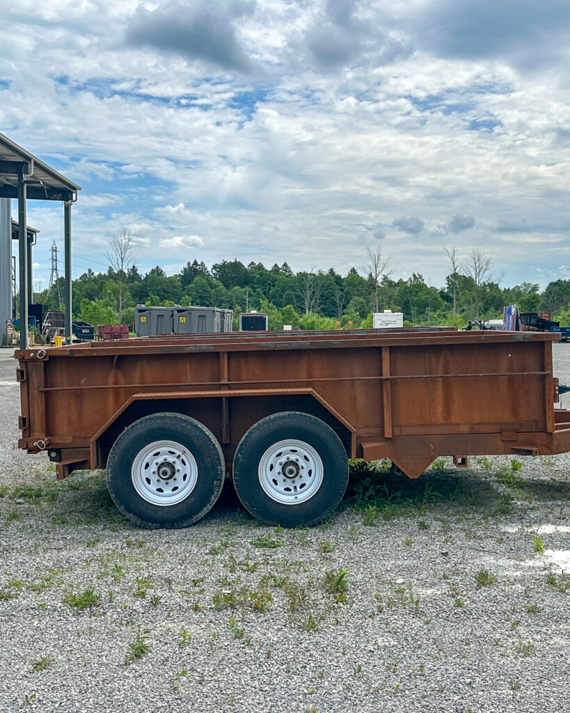 Side view of an unfinished MSA dump trailer frame with heavy-duty axles and raw steel finish.
