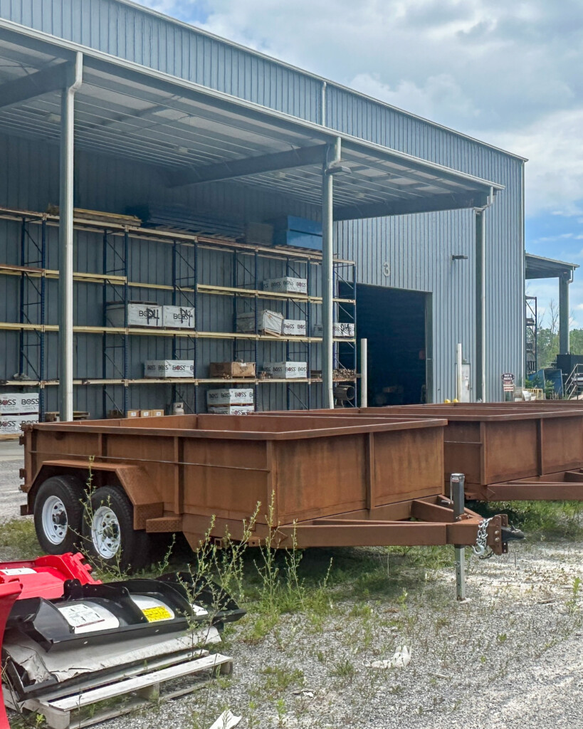 Perspective shot of multiple unfinished MSA dump trailers lined up outside General Welding & Fabricating.